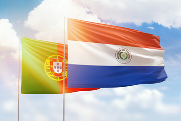 Sunny blue sky and flags of paraguay and portugal