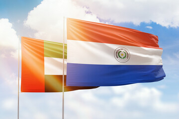 Sunny blue sky and flags of paraguay and uae