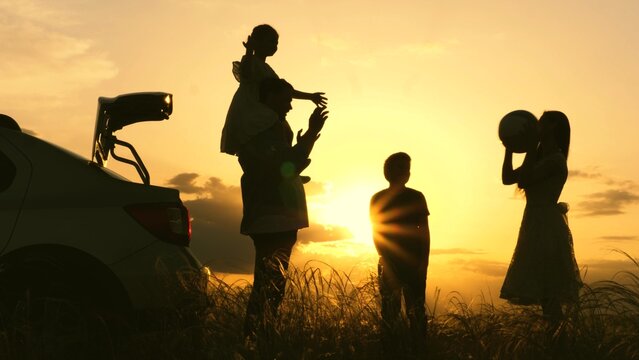 Father Mother Child Play With Ball Rays Sun Laugh Joyfully. Happy Family Playing With Ball Near Car Sunset. Childhood Dream Trip. Kid With Parents Picnic Forest. Silhouette Happy Family With Children.