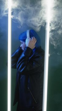 Music vibe. Song chill. Futuristic technology. Inspired dancing woman in headphones enjoying playlist in LED lamp light isolated on dark background.