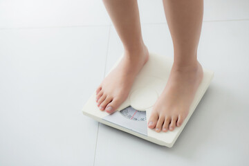 Closeup foot of woman standing on scales measuring for control weight in the room, overweight and dieting, health and weightloss, examining fat with weighing, indoor, healthy concepts.