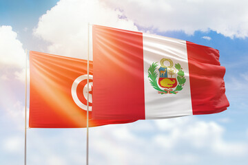 Sunny blue sky and flags of peru and tunisia