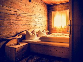 cozy warm light bedroom with on big double bed in a wooden holiday chalet at a rustic hut in the...