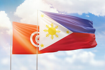 Sunny blue sky and flags of philippines and tunisia