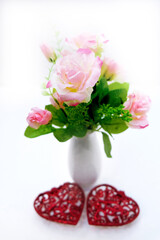 Artificial flower and white vase on white background, decoration with  red hearts, wedding interior detail close up