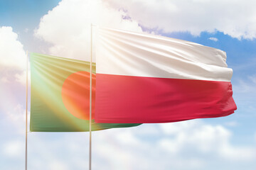 Sunny blue sky and flags of poland and bangladesh