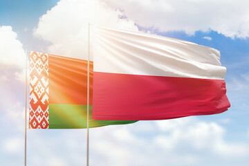 Sunny blue sky and flags of poland and belarus