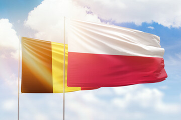 Sunny blue sky and flags of poland and belgium