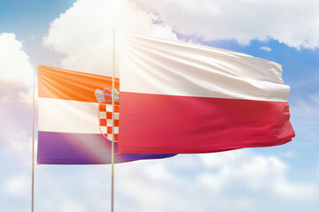 Sunny blue sky and flags of poland and croatia