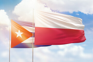 Sunny blue sky and flags of poland and cuba