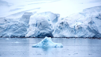 Iceberg floating in the bay, in front of a glacier at Portal Point in Antarctica