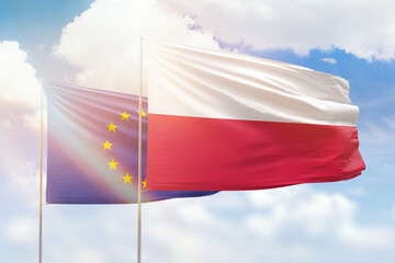 Sunny blue sky and flags of poland and european union
