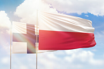 Sunny blue sky and flags of poland and finland