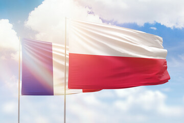 Sunny blue sky and flags of poland and france