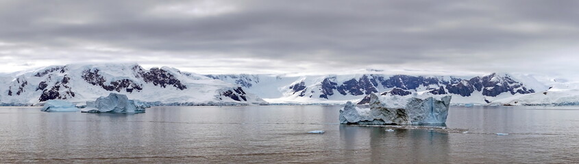 Panorama of icebergs floating in the bay, in front of snow covered moutains at Portal Point in...