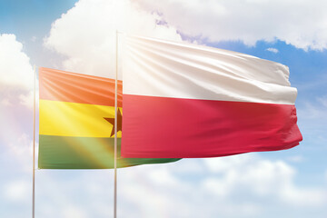 Sunny blue sky and flags of poland and ghana