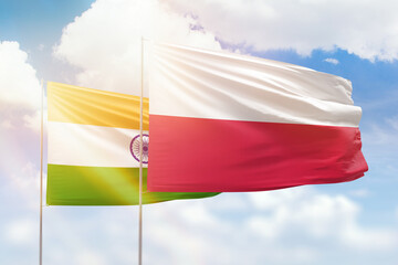 Sunny blue sky and flags of poland and india