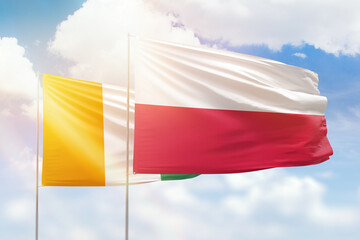 Sunny blue sky and flags of poland and ivory coast