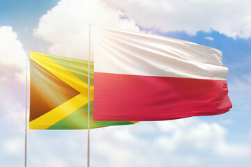 Sunny blue sky and flags of poland and jamaica