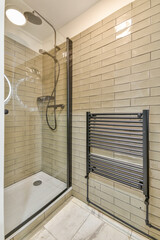 Shower faucets attached to tiled wall near glass partition and ornamental curtail in washroom at...