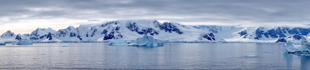 Panorama of icebergs floating in the bay, in front of snow covered moutains at Portal Point in...