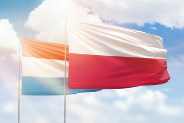 Sunny blue sky and flags of poland and luxembourg