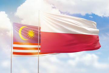 Sunny blue sky and flags of poland and malaysia