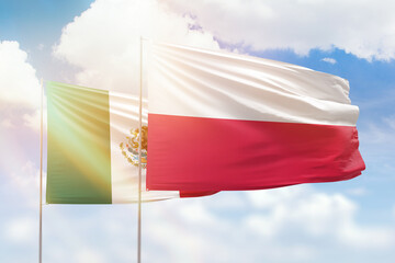 Sunny blue sky and flags of poland and mexico