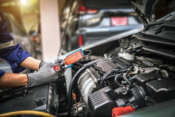 Fototapeta Close up hand of auto mechanic using measuring manifold gauge check the refrigerant and filling car air conditioner for fix and checking for repair service support maintenance and car insurance. obraz