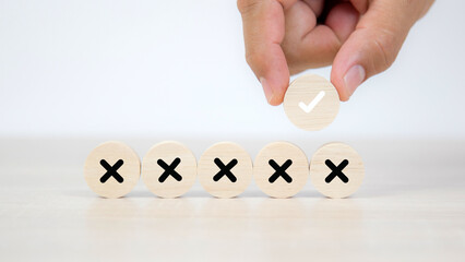 Hand choose check mark on wooden toy with cross symbol for true or false changing mindset or way of...