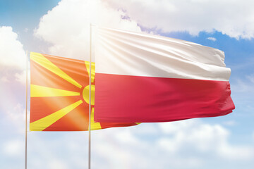 Sunny blue sky and flags of poland and north macedonia