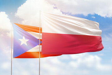 Sunny blue sky and flags of poland and puerto rico