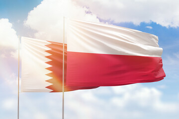 Sunny blue sky and flags of poland and qatar