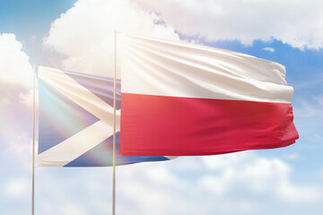 Sunny blue sky and flags of poland and scotland