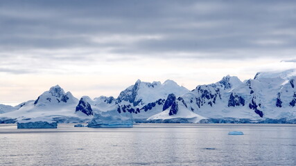 Icebergs floating in the bay in front of snow covered mountains at Portal Point in Antarctica