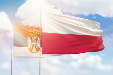 Sunny blue sky and flags of poland and serbia