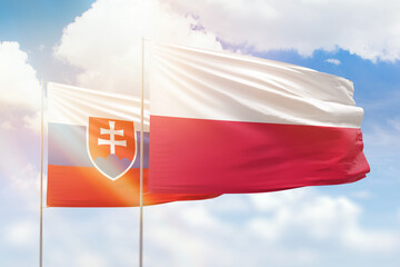 Sunny blue sky and flags of poland and slovakia