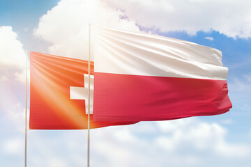 Sunny blue sky and flags of poland and switzerland
