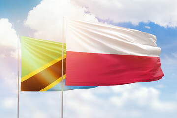 Sunny blue sky and flags of poland and tanzania
