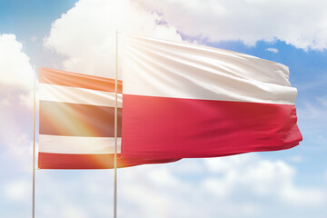 Sunny blue sky and flags of poland and thailand