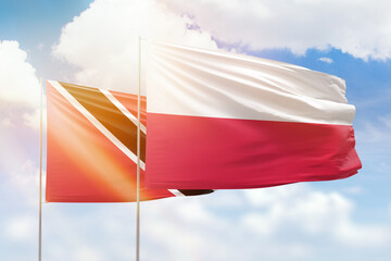 Sunny blue sky and flags of poland and trinidad and tobago