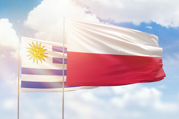 Sunny blue sky and flags of poland and uruguay