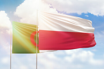 Sunny blue sky and flags of poland and algeria