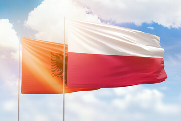 Sunny blue sky and flags of poland and albania
