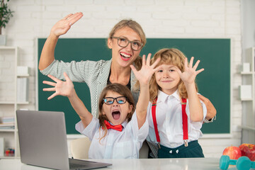 Excited teacher with a school kids learning at laptop computer, studying with online education....