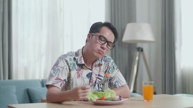 Asian Man Holding His Cheek And Shaking Her Head Due To Hating Eating Healthy Food While Having A Meal At Home
