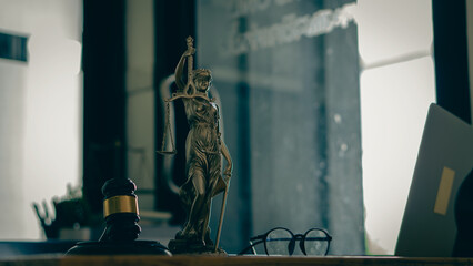Law concept, hammer, and goddess of injustice, law tiger, and laptop on a table in a lawyer's...
