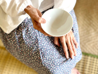空っぽの茶碗を持つ高齢女性の手