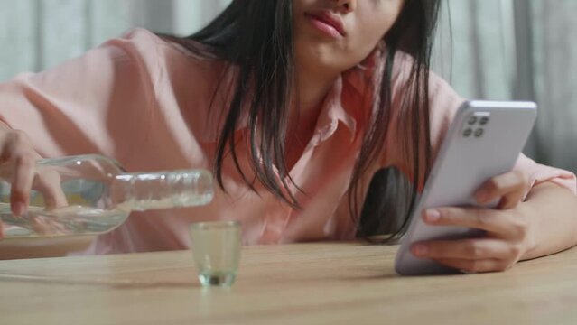 Close Up Of Drunk, Depressed Asian Woman Drinking Vodka From Glass During Using Smartphone At Home
