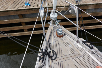 An elegant two masted sailboat (ketch) moored to a pier in a yacht marina. Wooden teak deck,...
